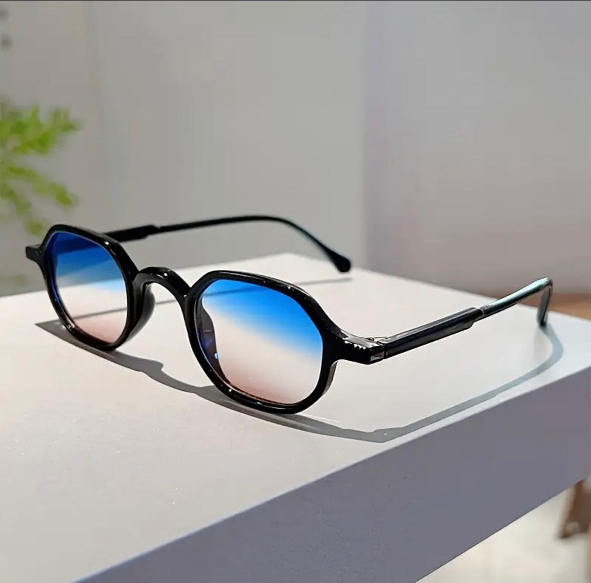 Sunglasses with blue gradient lenses on a white surface