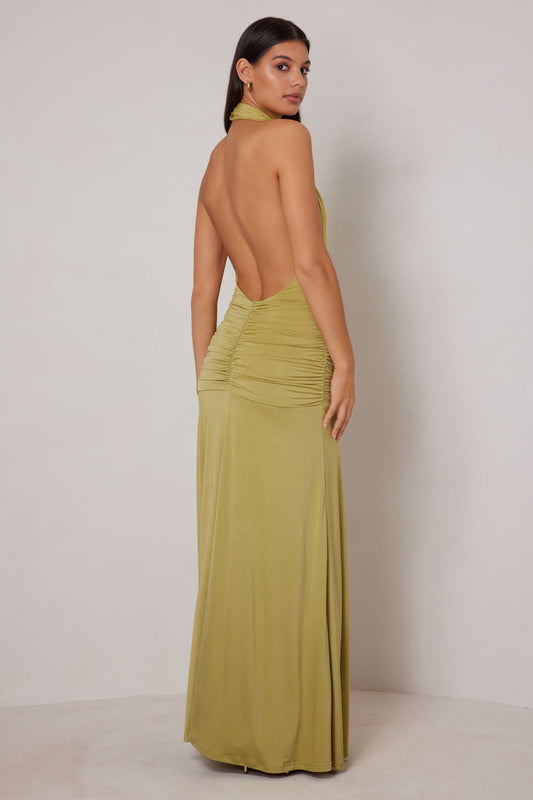 Woman wearing a green open-back dress against a plain background