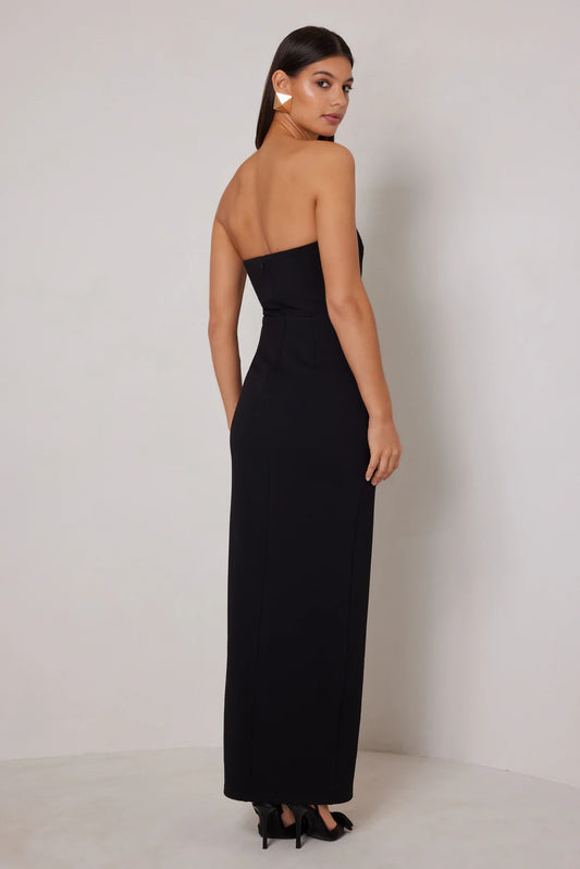 Woman wearing a black strapless gown against a white background