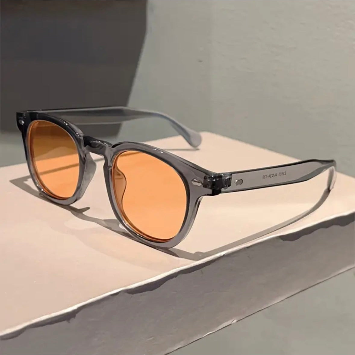 Sunglasses with orange lenses on a light gray surface