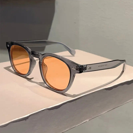 Sunglasses with orange lenses on a light gray surface