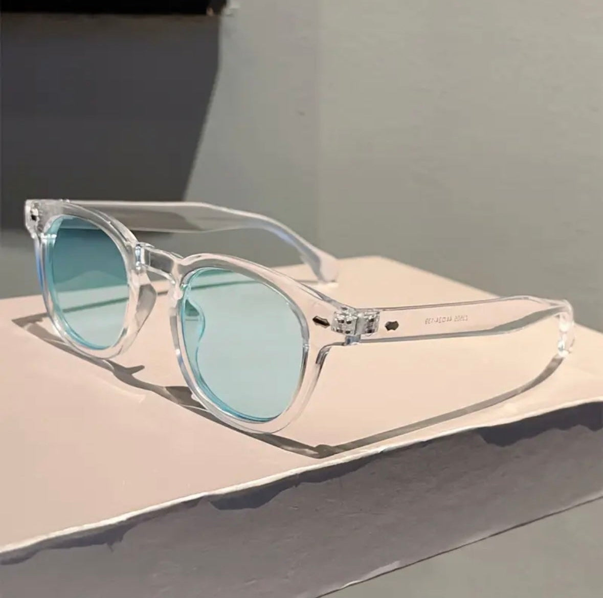 Clear sunglasses with blue lenses on a light surface