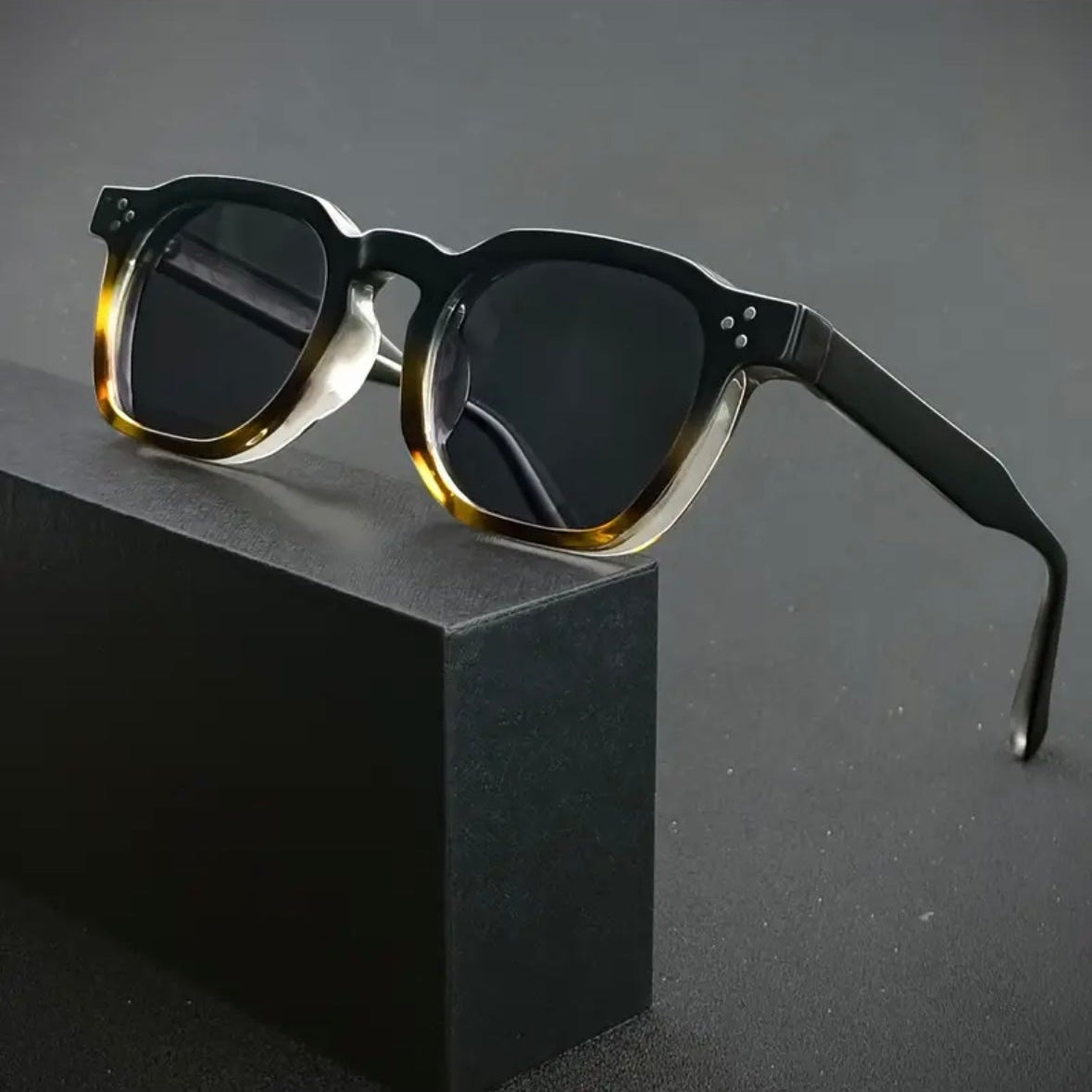 Sunglasses with a black frame and tortoiseshell accents on a dark background