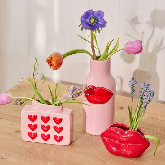 Three unique vases with flowers on a wooden surface