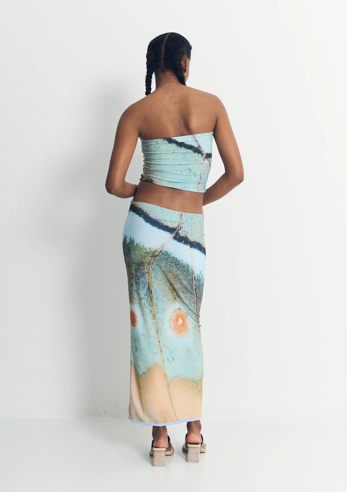 Woman wearing a strapless top and long skirt with nature-themed design on a white background