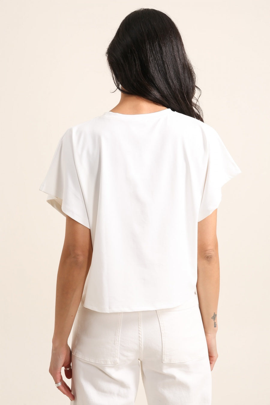 Person wearing a white top and pants on a beige background