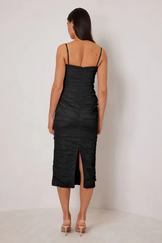 Woman wearing a black dress with thin straps and a slit on a white background