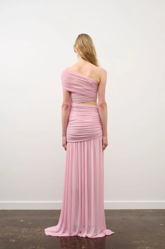 Woman wearing a pink one-shoulder dress against a white wall.