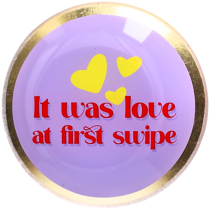Round purple magnet with yellow hearts and red text 'It was love at first swipe' on a white background.