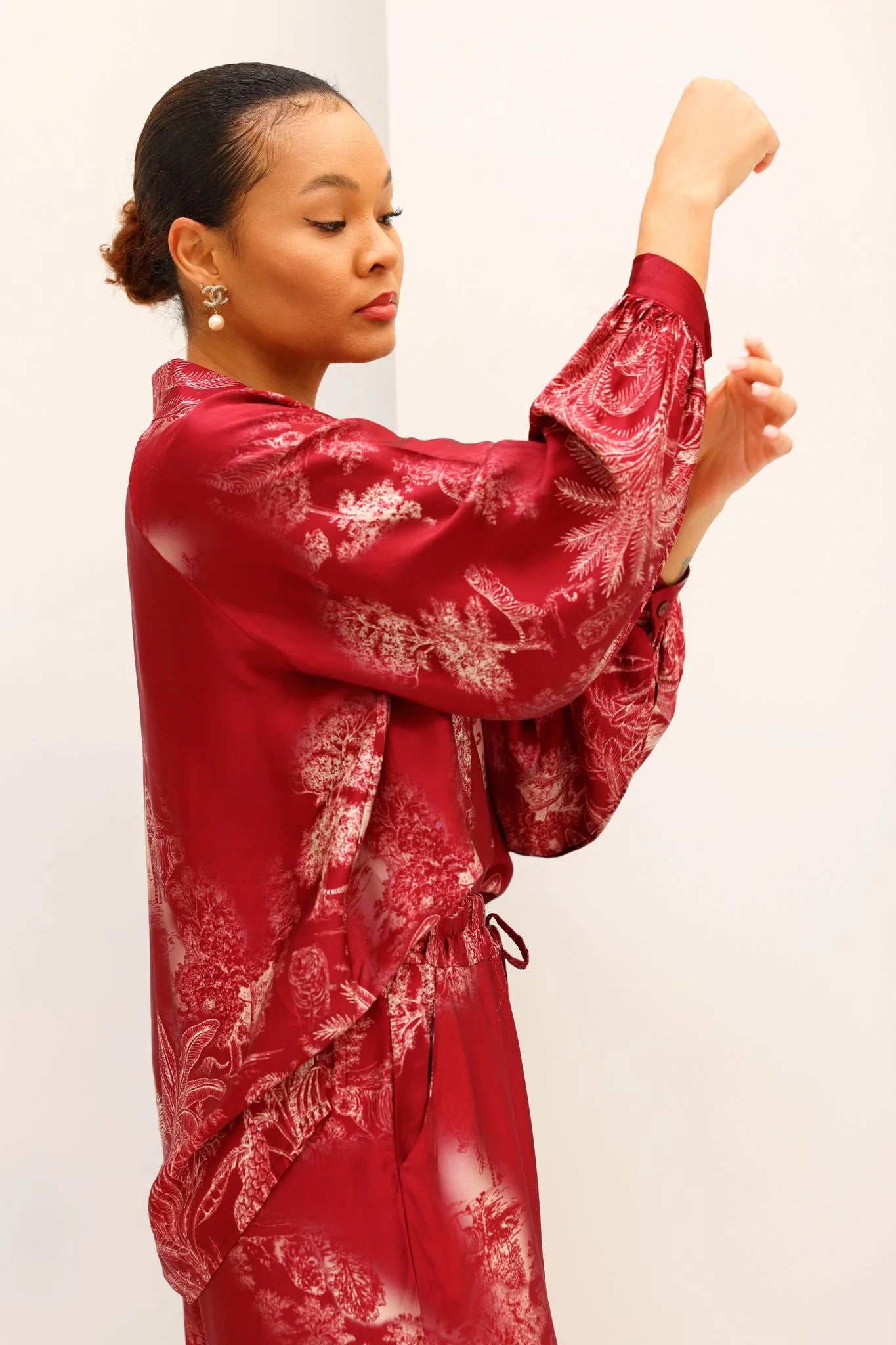 Woman wearing a red satin robe with white patterns on a plain background