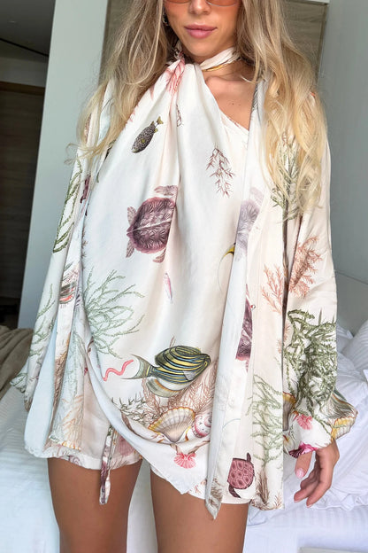 Woman wearing a floral kimono-style garment with nature-themed prints.
