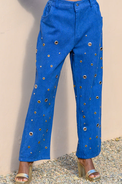 Blue pants with eyelet details on a neutral background