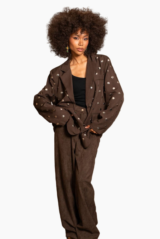 Woman wearing a brown outfit with a patterned jacket on a white background