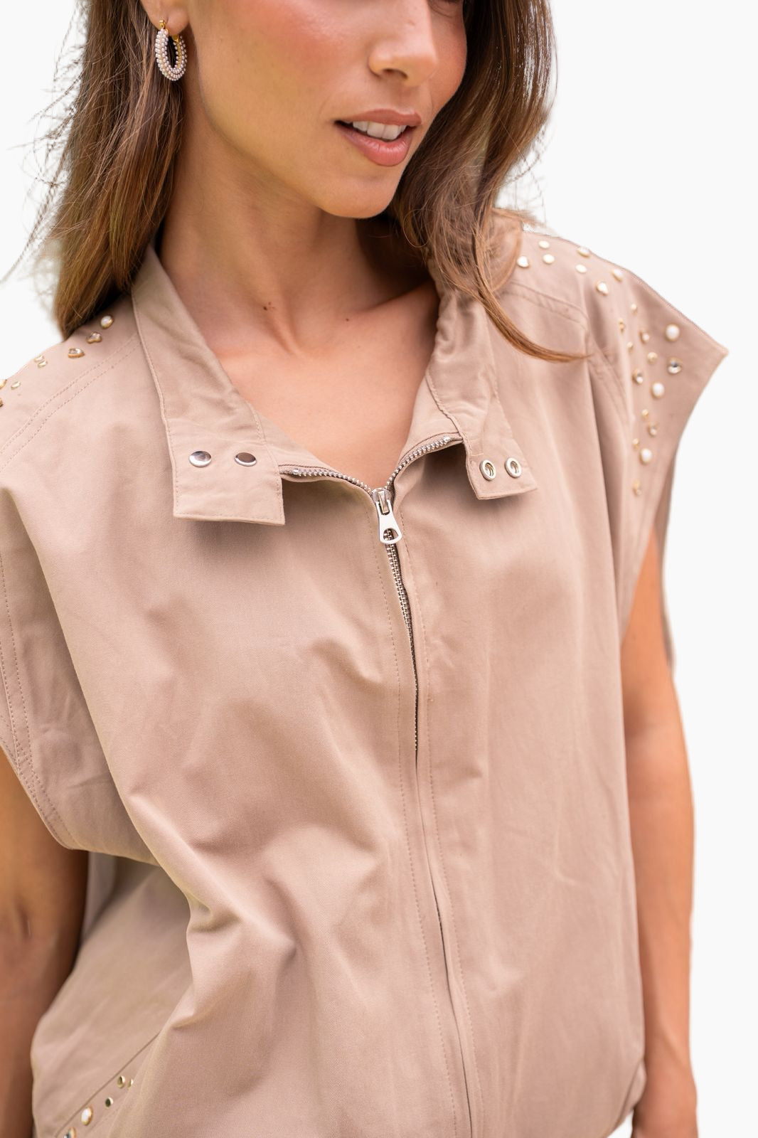 Beige sleeveless jacket with studded details on a white background