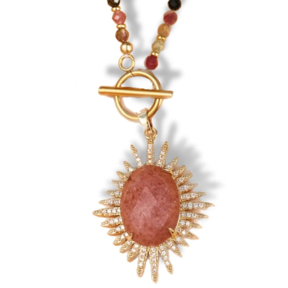 Necklace with a gold pendant and pink stone on a white background