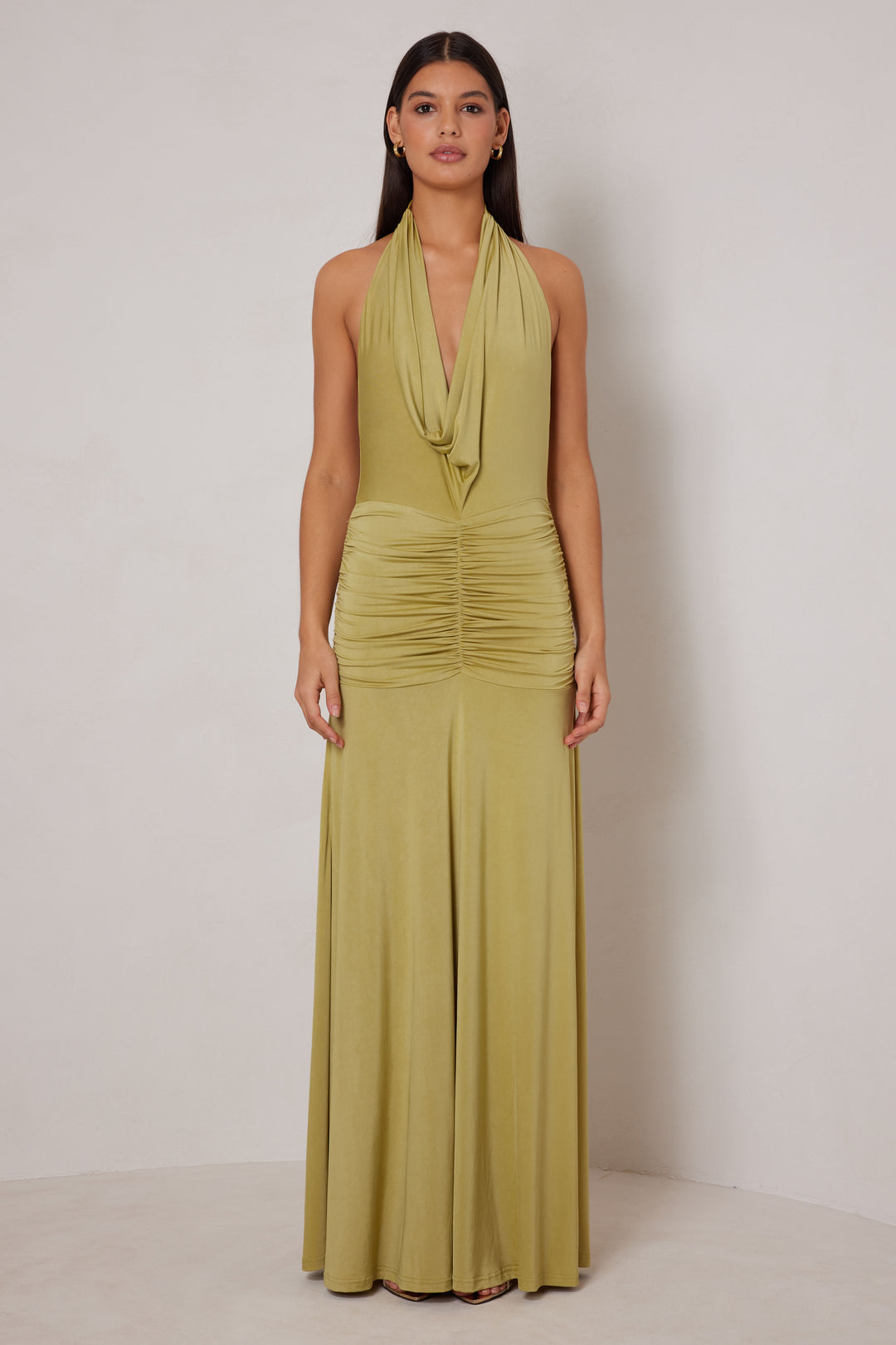 Woman wearing a green halter neck gown against a plain background