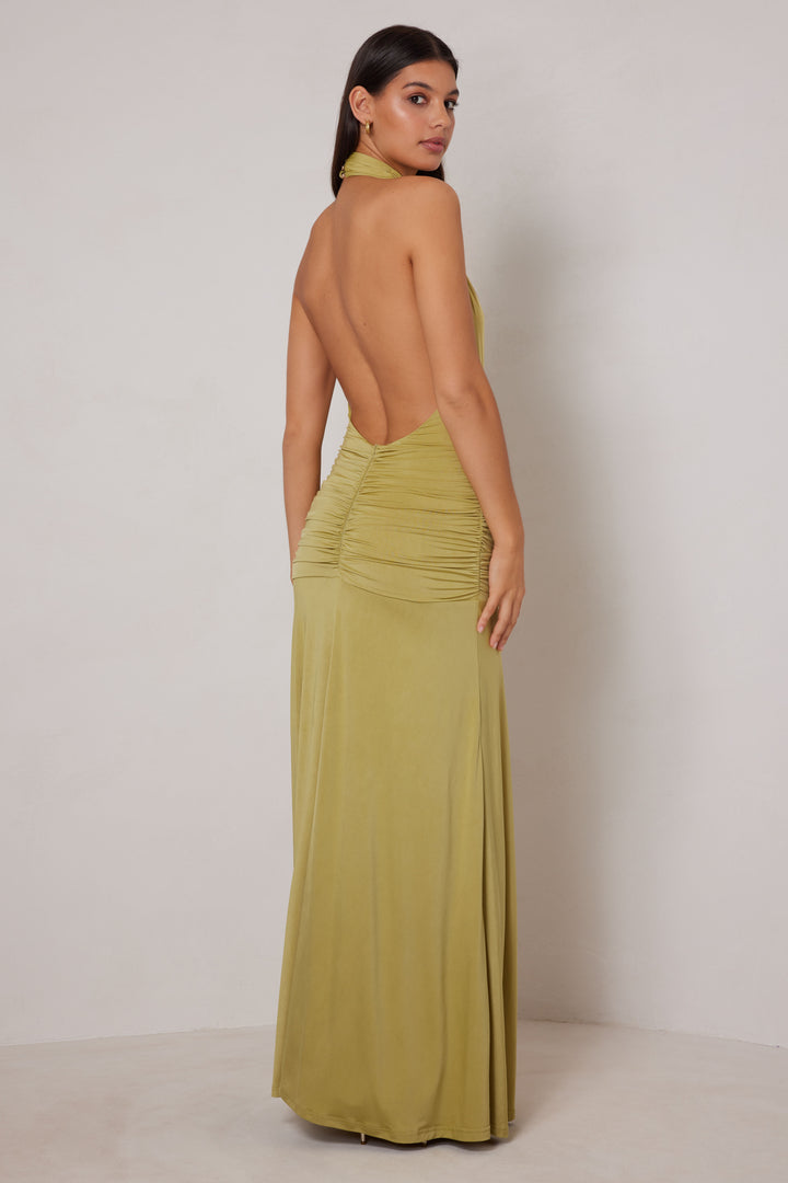 Woman wearing a green open-back dress against a plain background
