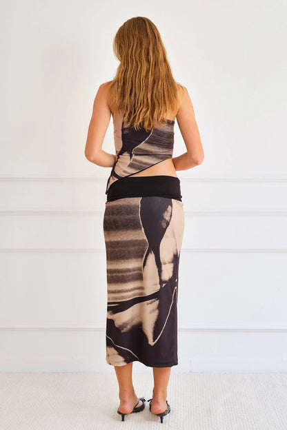 Woman wearing a black and brown patterned dress against a white background
