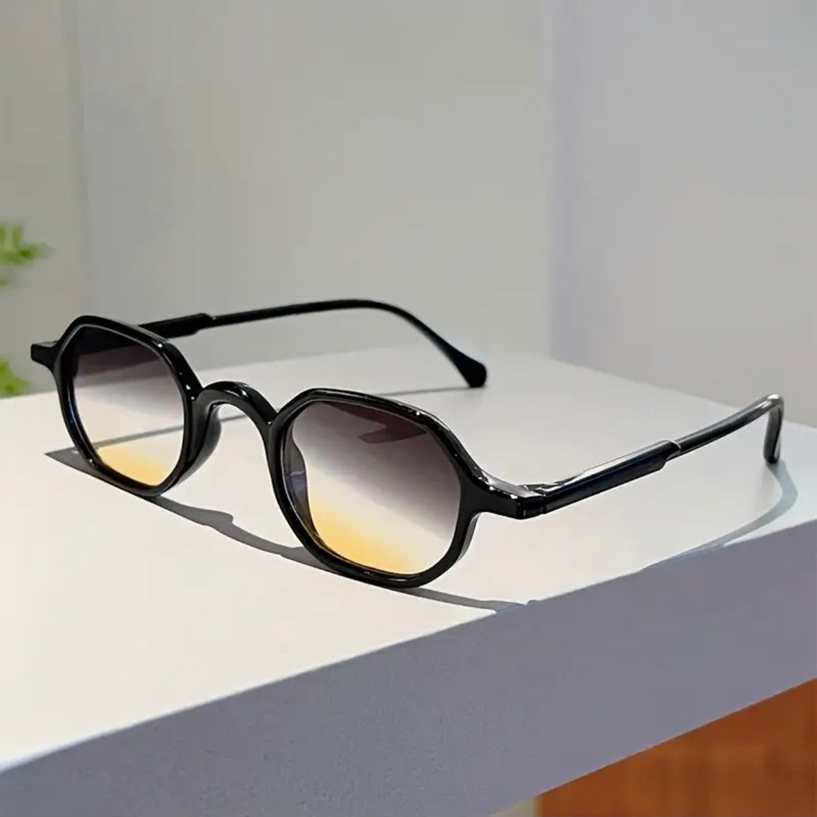 Sunglasses with black frame and gradient lenses on a light surface
