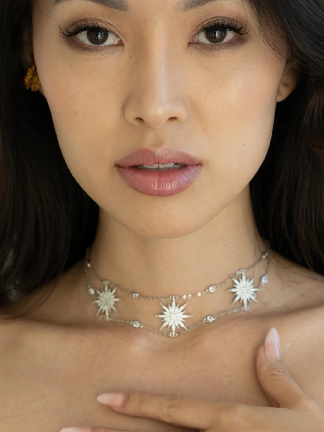 Close-up of a woman wearing a star-shaped necklace with a neutral background