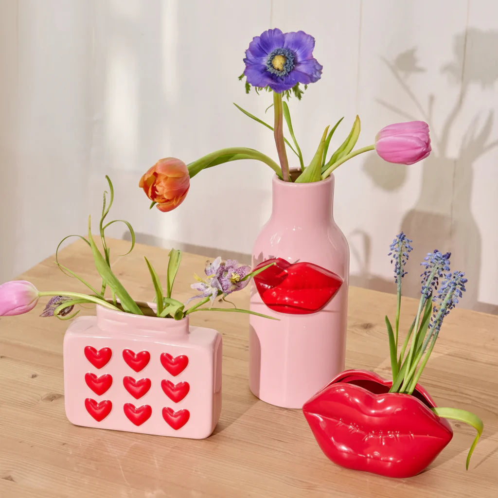 Three unique vases with flowers on a wooden surface