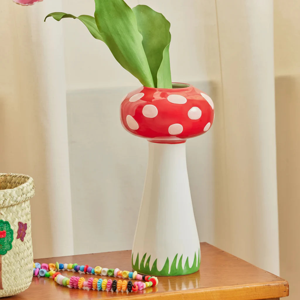 Mushroom-shaped vase with green plant on a wooden surface