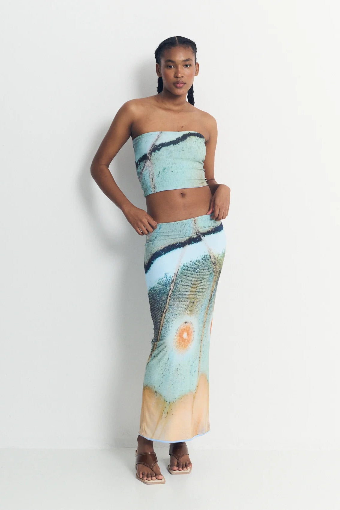 Woman wearing a strapless top and long skirt with abstract design on a white background