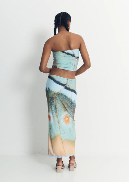 Woman wearing a strapless top and long skirt with nature-themed design on a white background