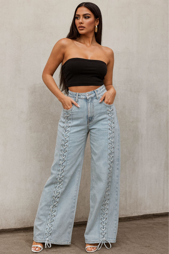 Woman wearing a black strapless top and light blue jeans with lace-up sides against a neutral background.