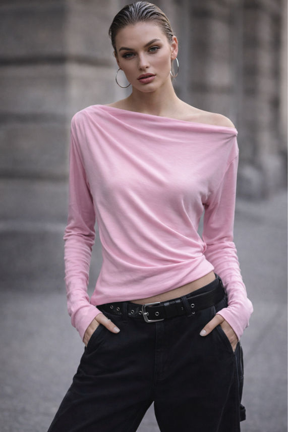 Woman wearing a pink off-shoulder top and black pants against a blurred urban background