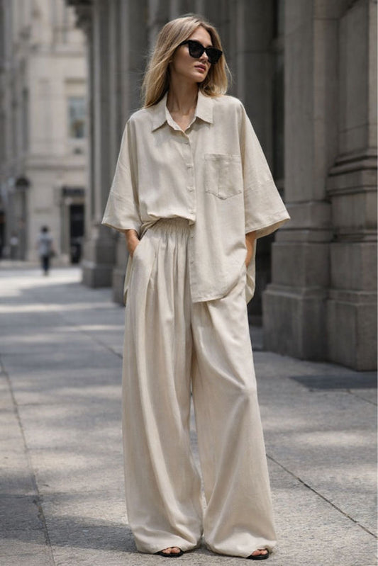Woman wearing a beige outfit with sunglasses on a city street.