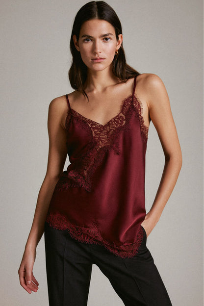 Woman wearing a burgundy lace camisole against a neutral background