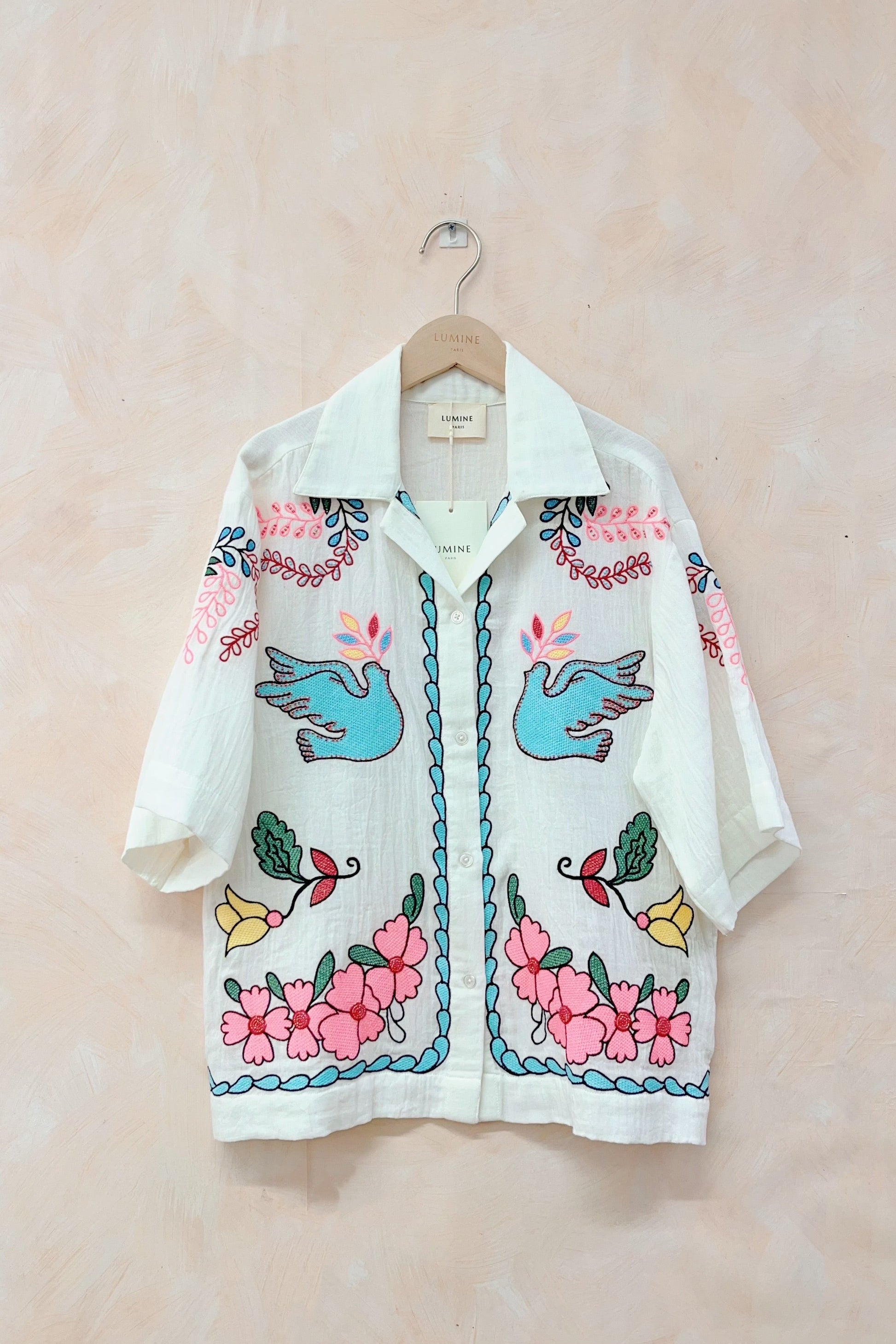 Embroidered shirt with floral and bird designs on a beige background