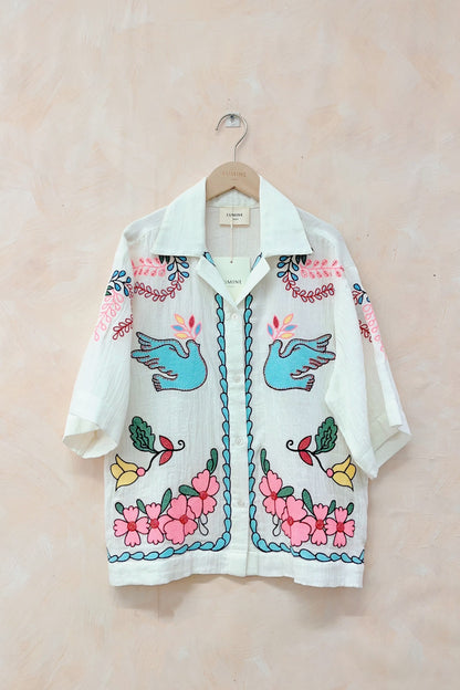 Embroidered shirt with floral and bird designs on a beige background