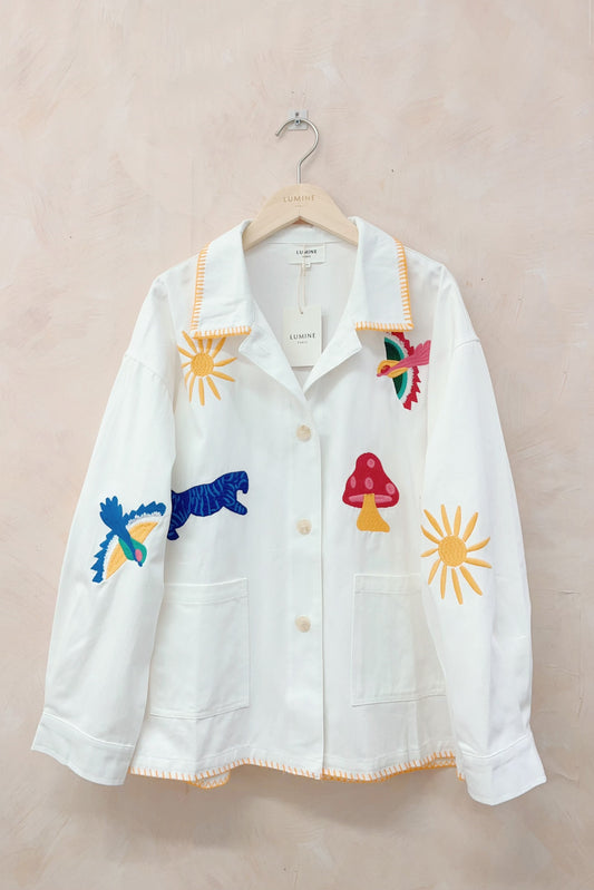 White shirt with colorful embroidered designs on a beige background