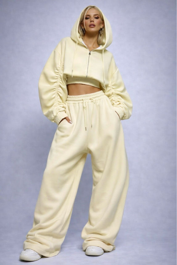 Person wearing a beige tracksuit against a light purple background