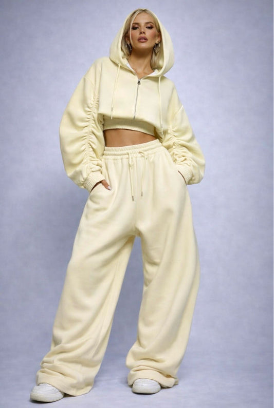 Person wearing a beige tracksuit against a light purple background