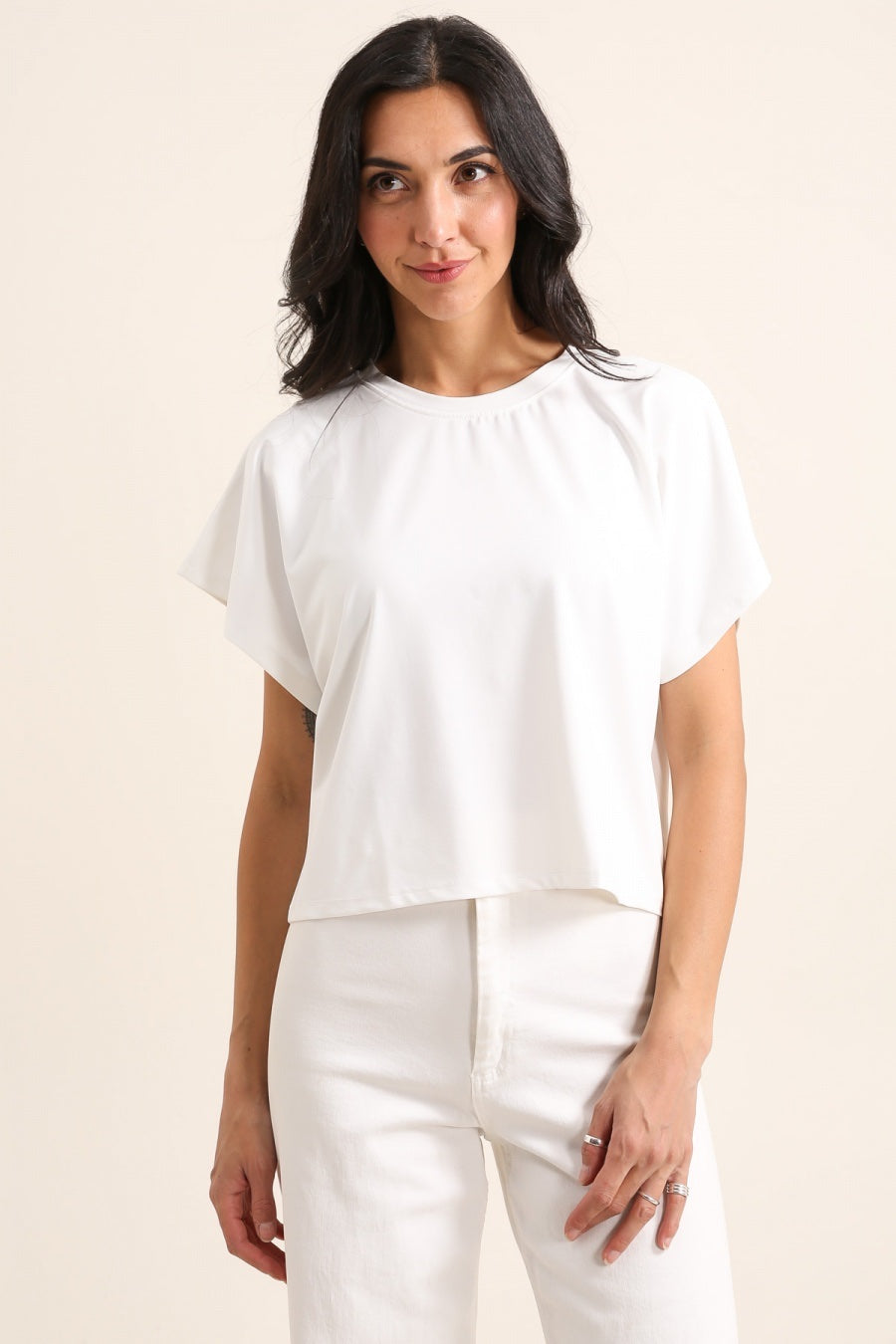 Woman wearing a white blouse and pants on a beige background