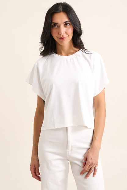 Woman wearing a white blouse and pants on a beige background