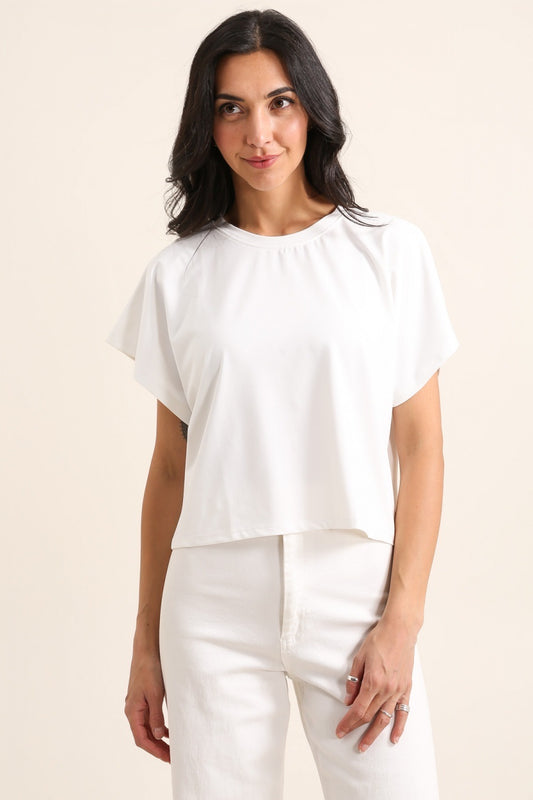 Woman wearing a white blouse and pants on a beige background