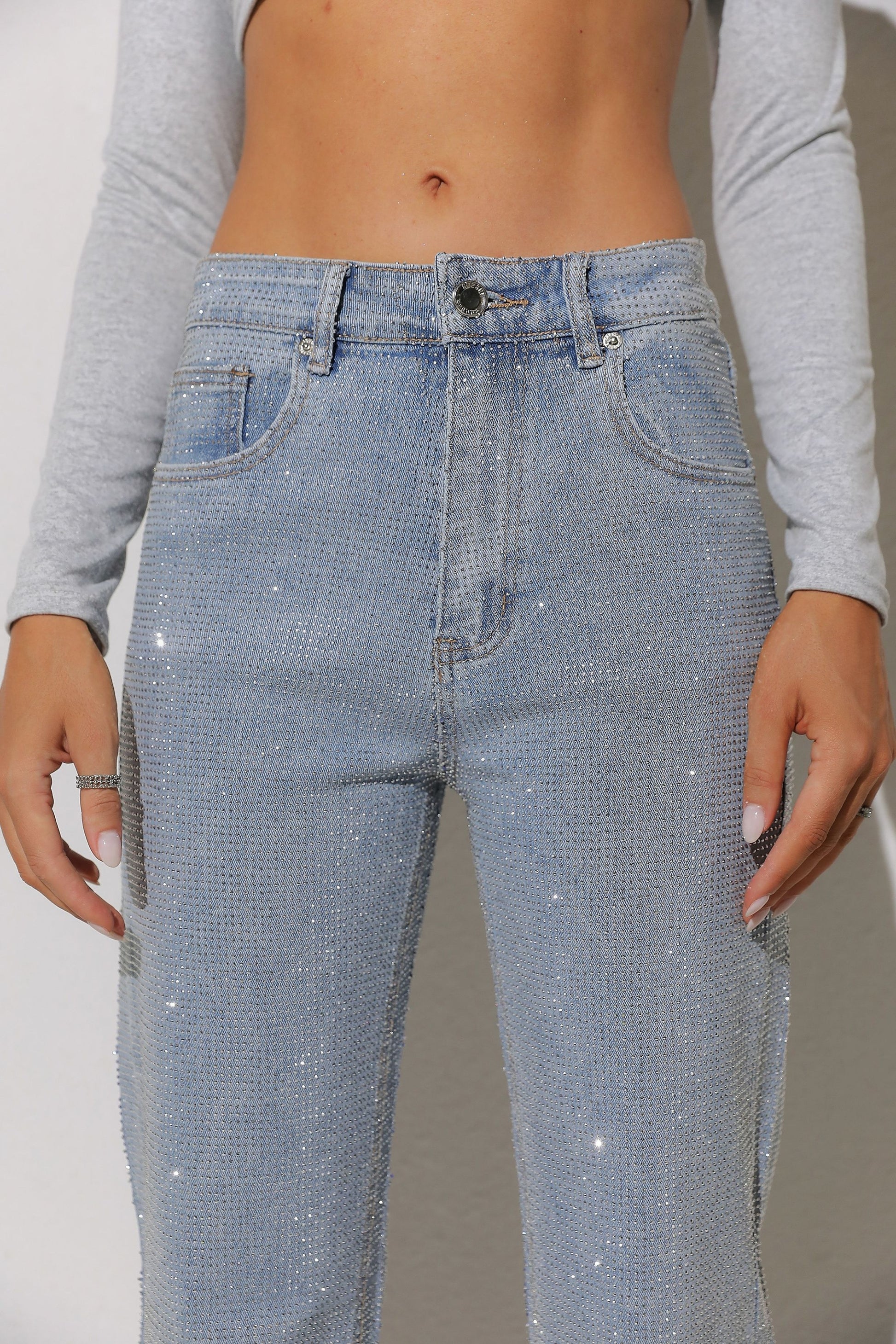 Person wearing light blue jeans with a subtle pattern on a plain background