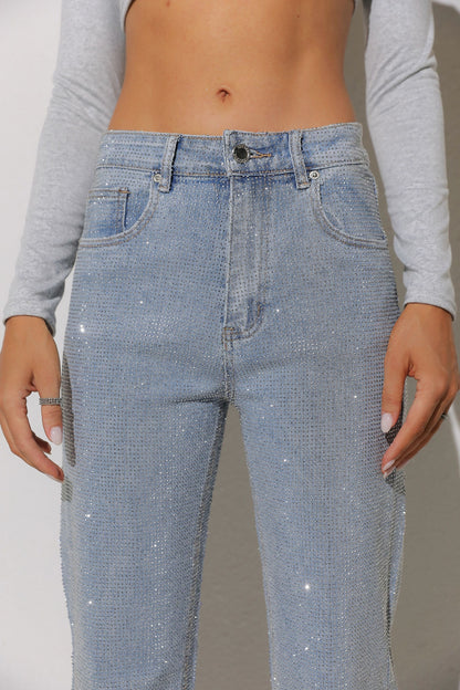 Person wearing light blue jeans with a subtle pattern on a plain background