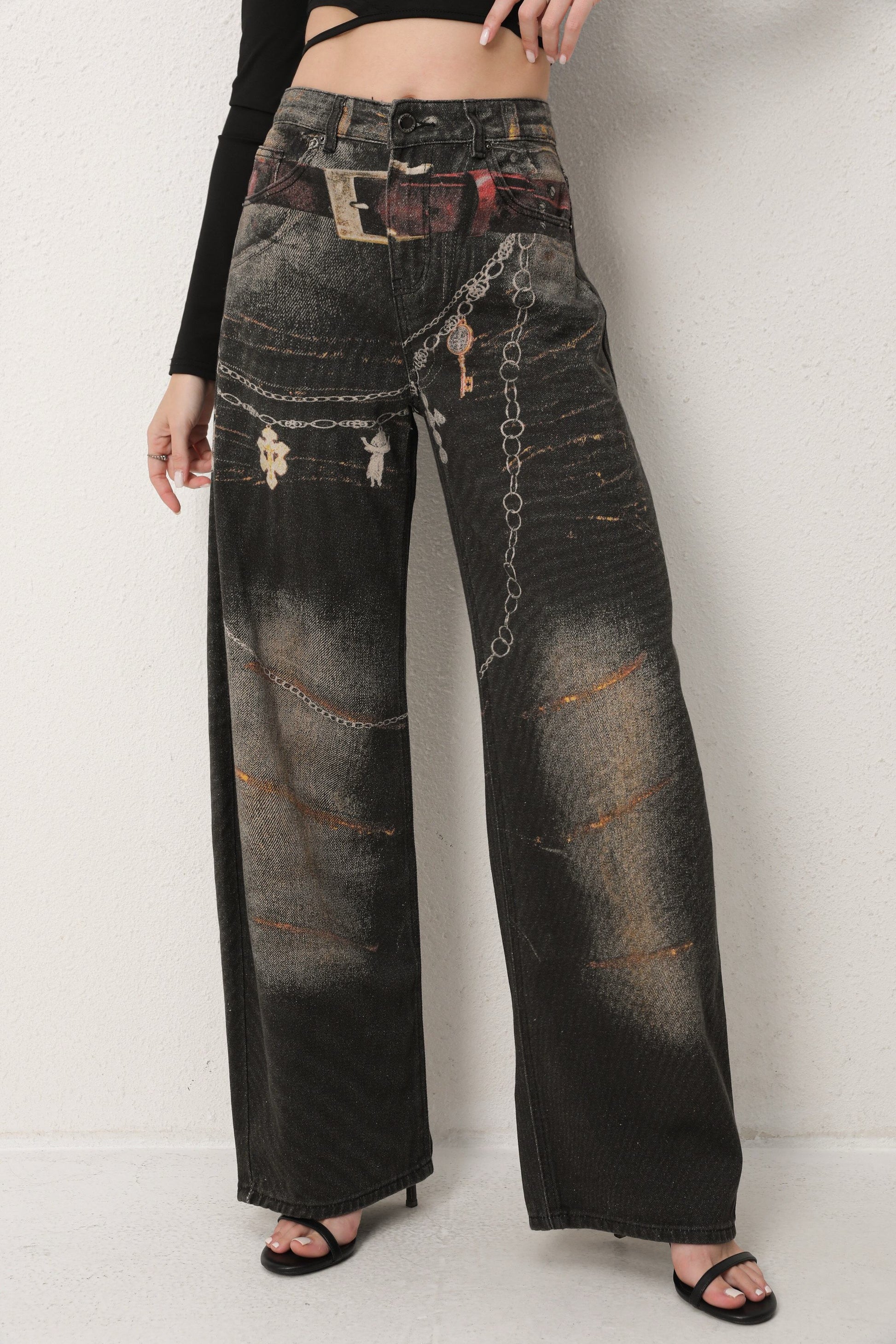 Distressed black jeans with decorative elements on a white background