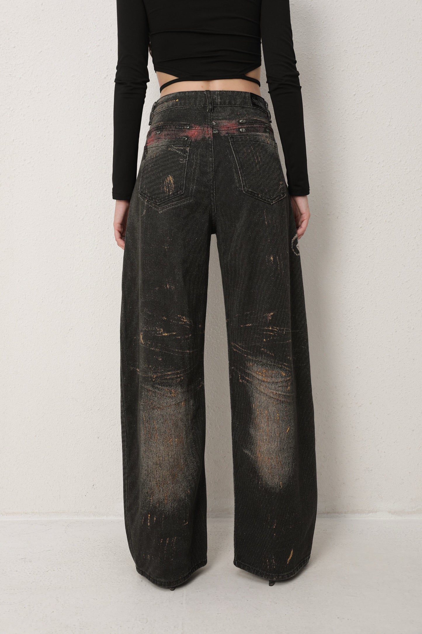 Person wearing dark distressed jeans on a plain background