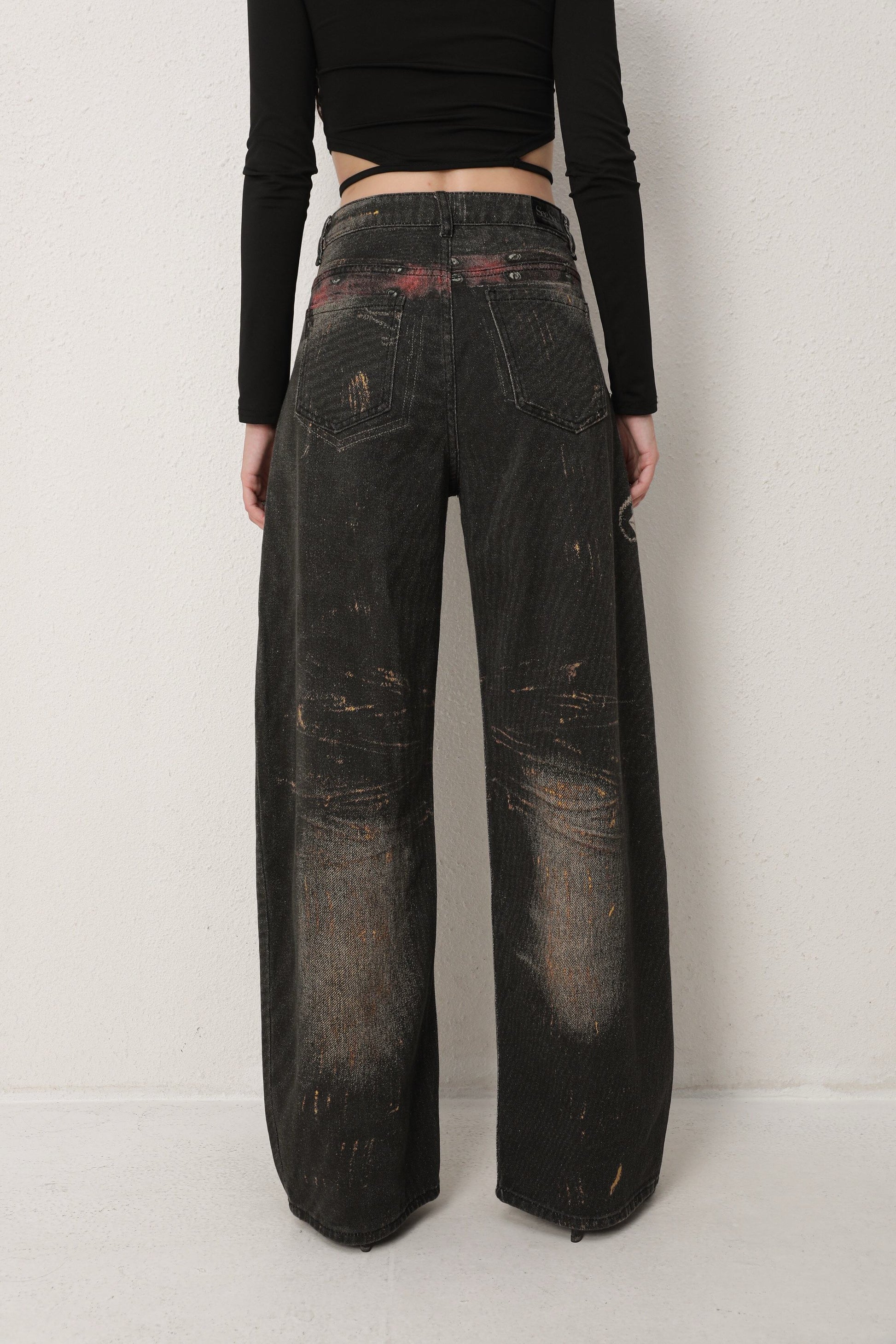 Person wearing dark distressed jeans on a plain background