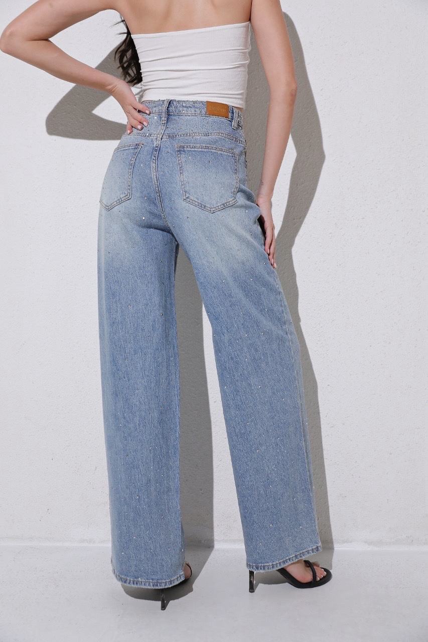 Person wearing light blue jeans and a white top against a plain background