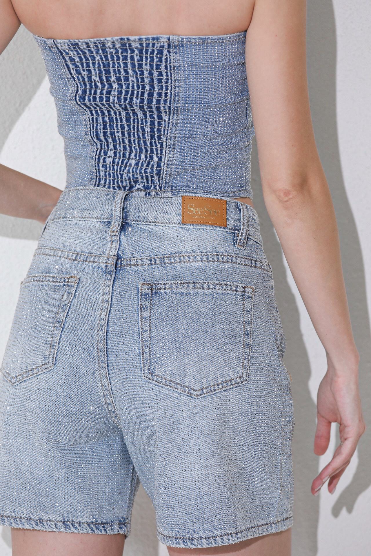 These are light-wash blue denim shorts featuring all-over rhinestone embellishments and a high-rise waist.