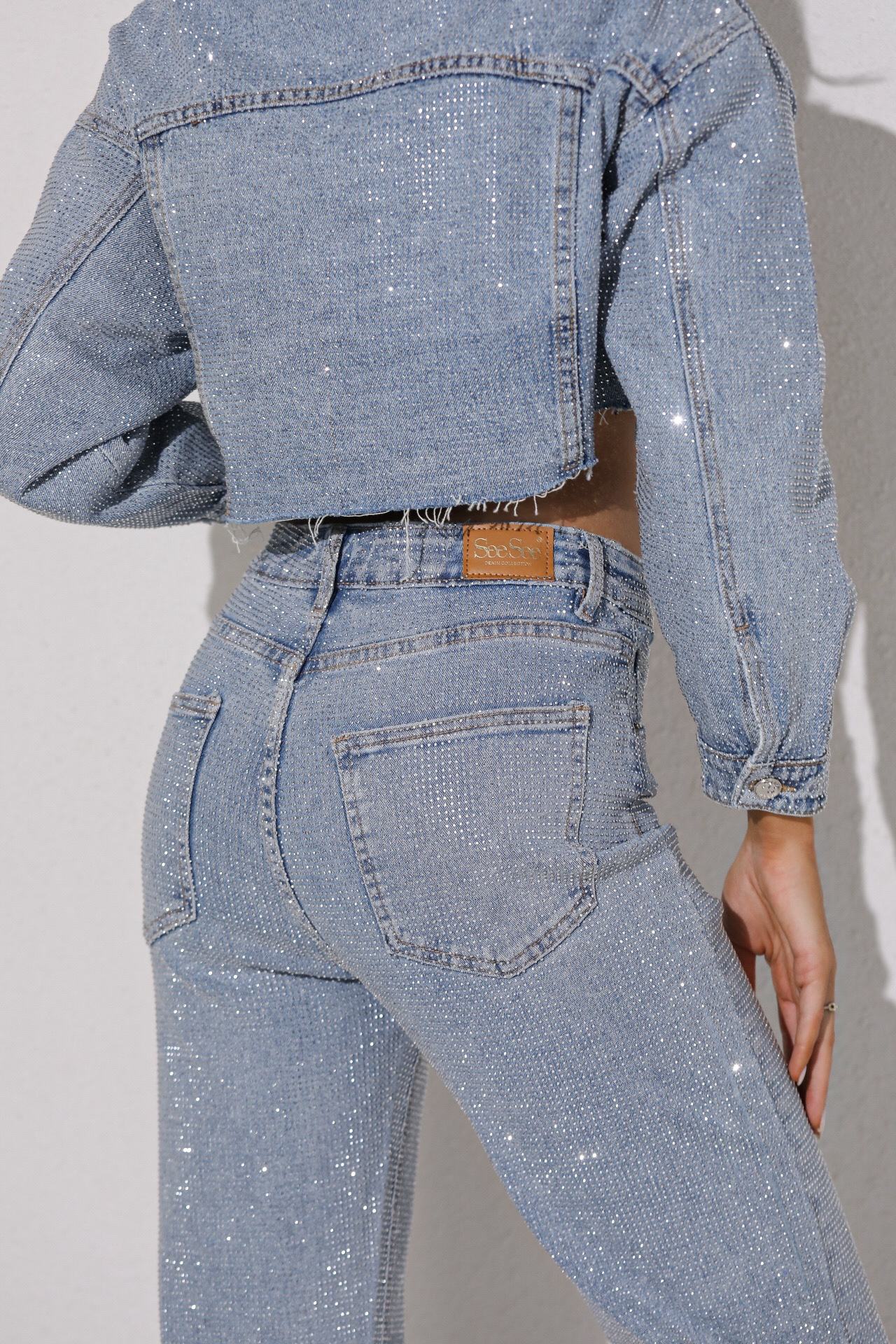 Person wearing a blue denim jacket and jeans on a plain background