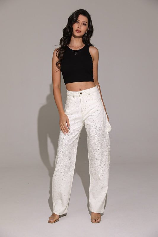 This outfit features a black cropped tank top paired with high-waisted white balloon carpenter jeans covered in shimmering rhinestone embellishments and styled with nude square-toe heeled sandals.