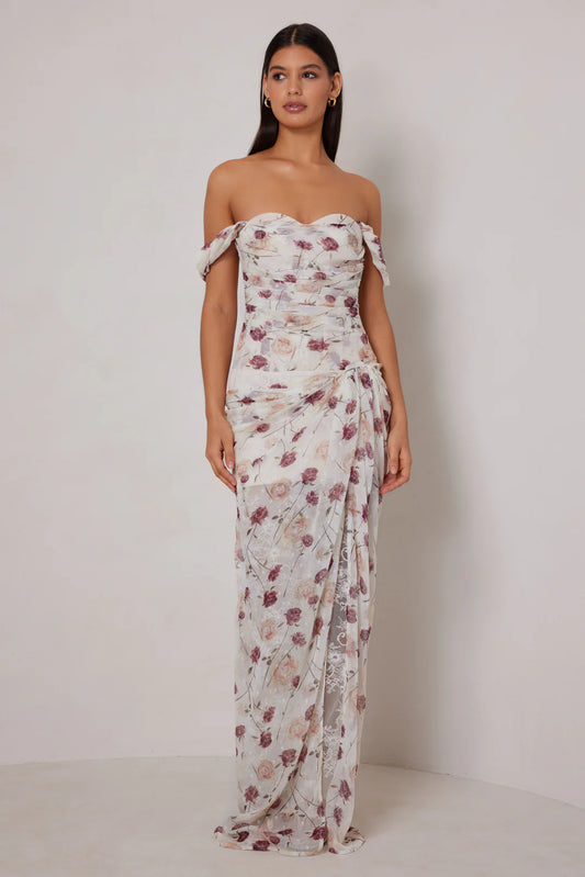 Woman wearing a floral strapless gown against a plain background